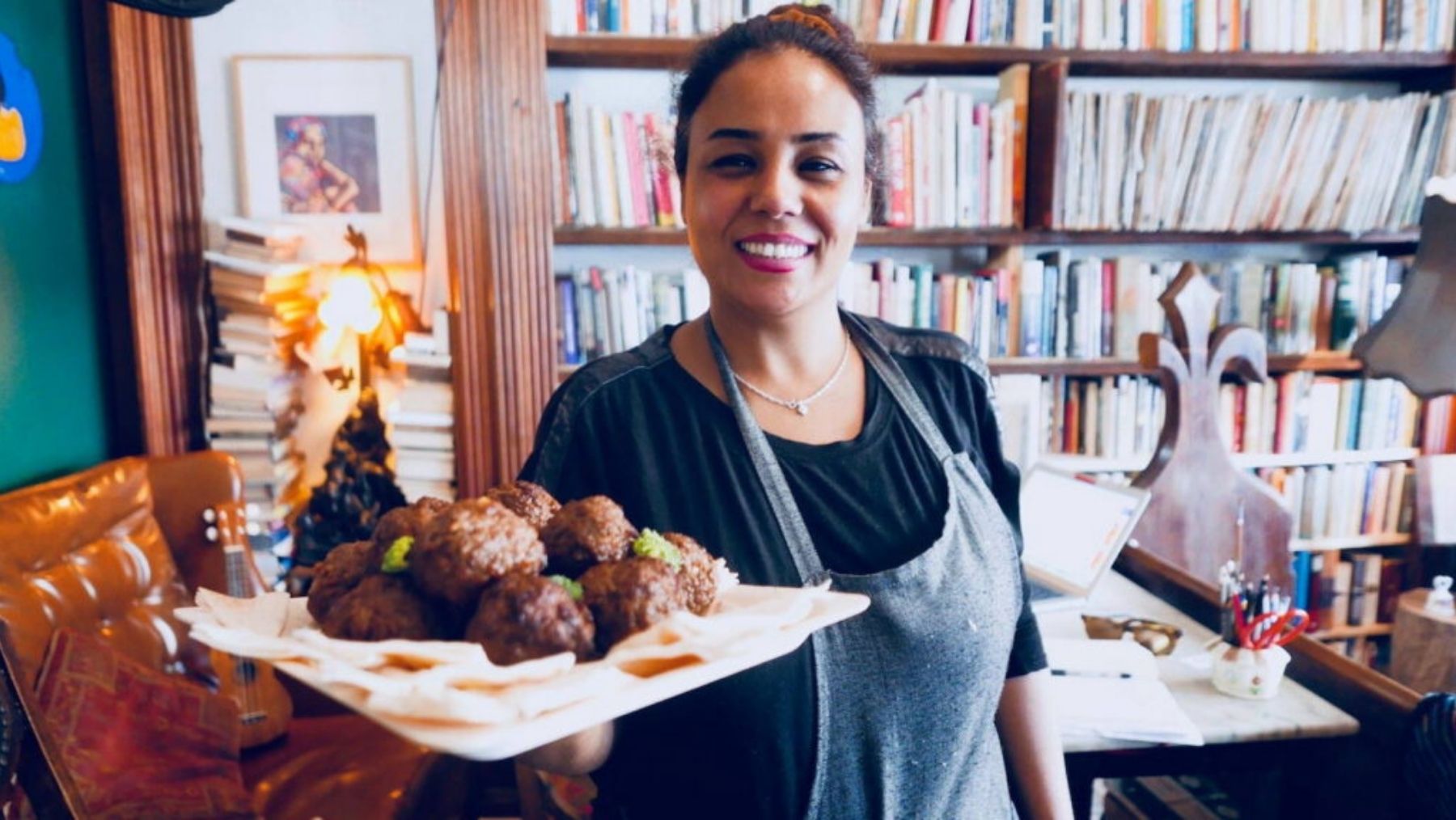 a woman holds a plate of meatballs