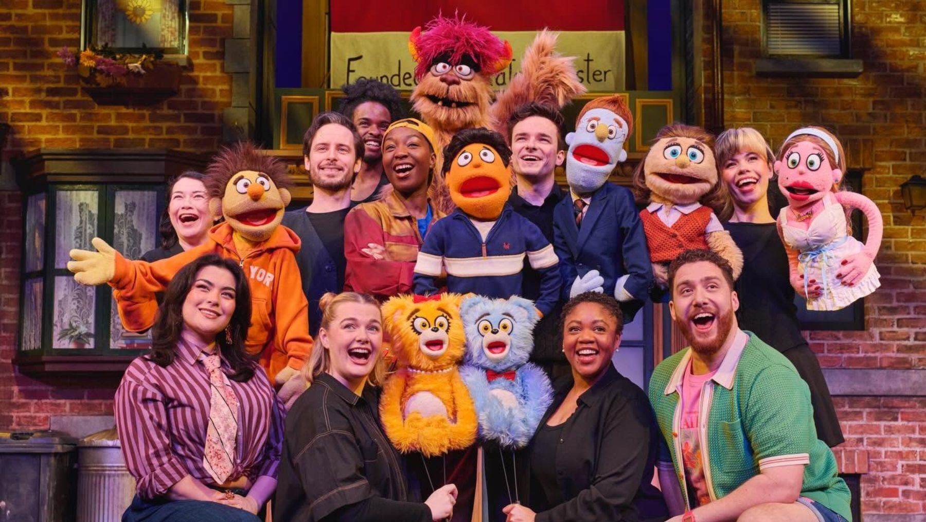 a cast holds up avenue q puppets